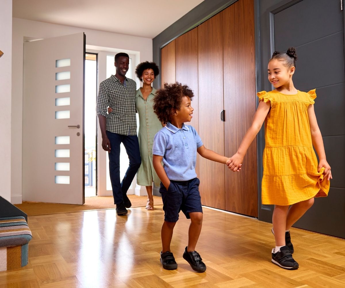 Man and woman with 2 kids walking into a house