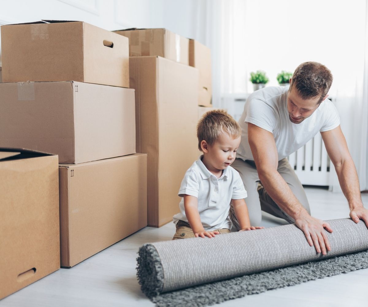 Man and boy rolling rug with moving boxes