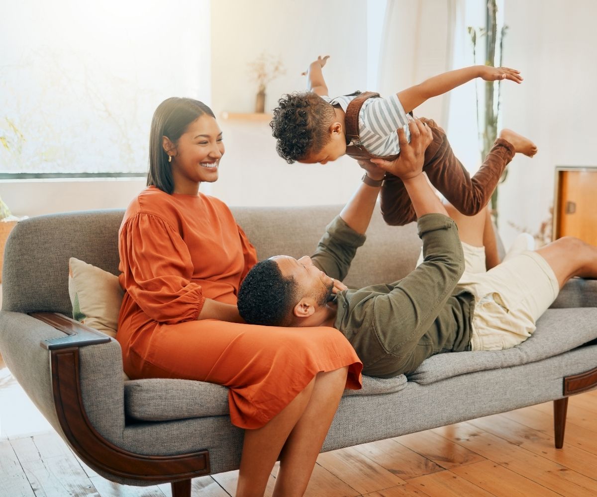Man and woman playing on couch with their son