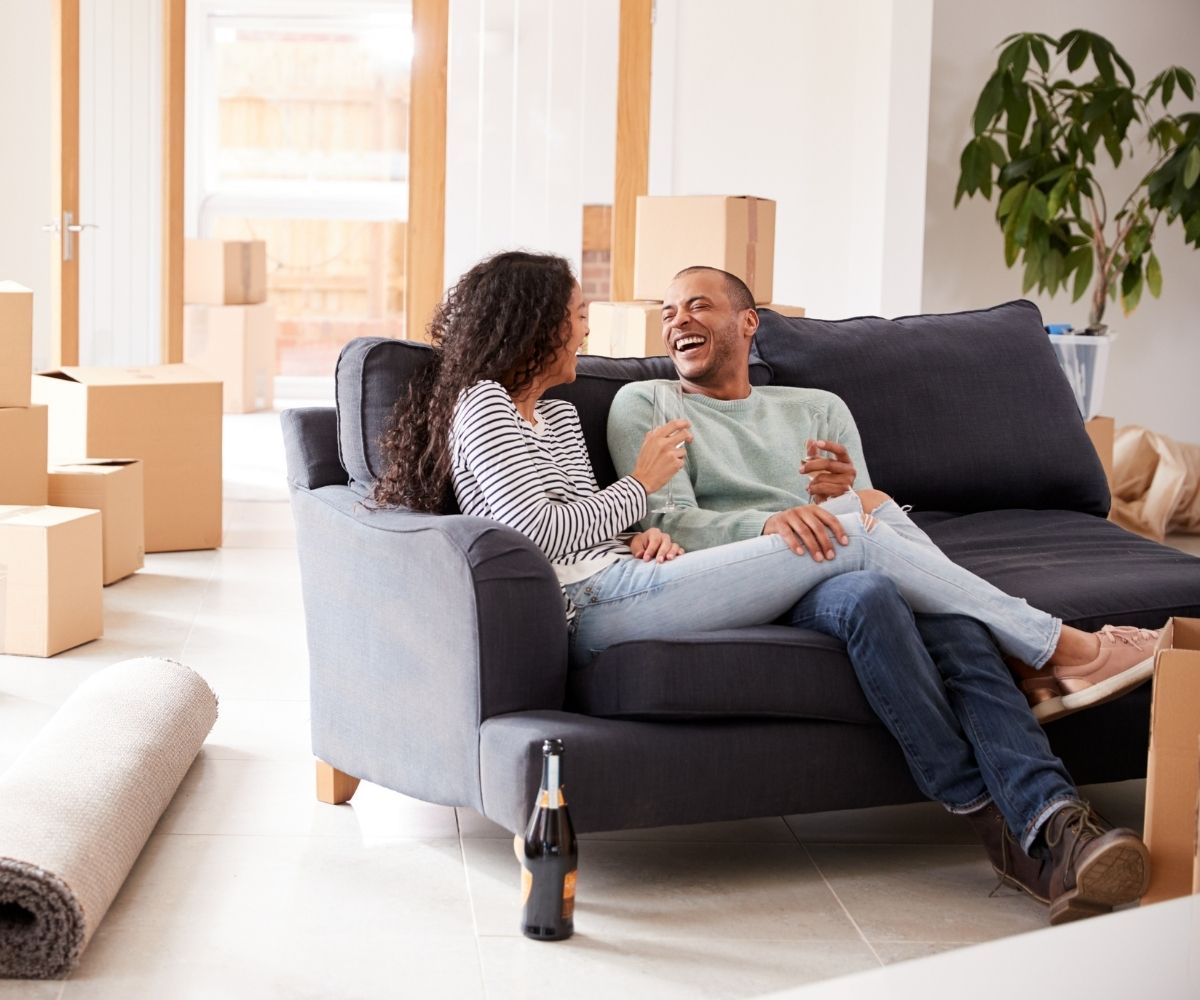 Couple sitting on couch with moving boxes