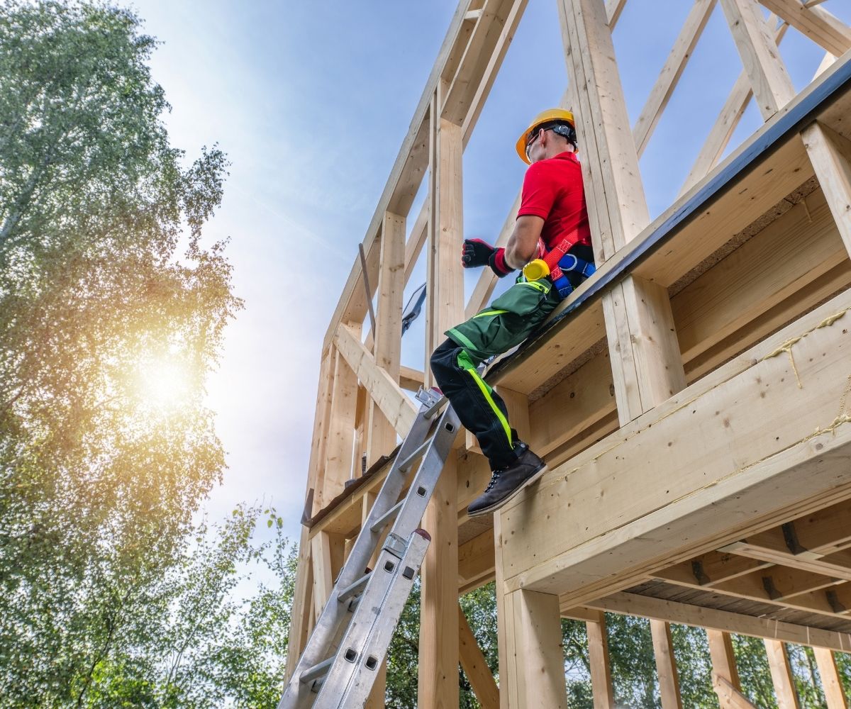 Man sitting on wood framing of house being built