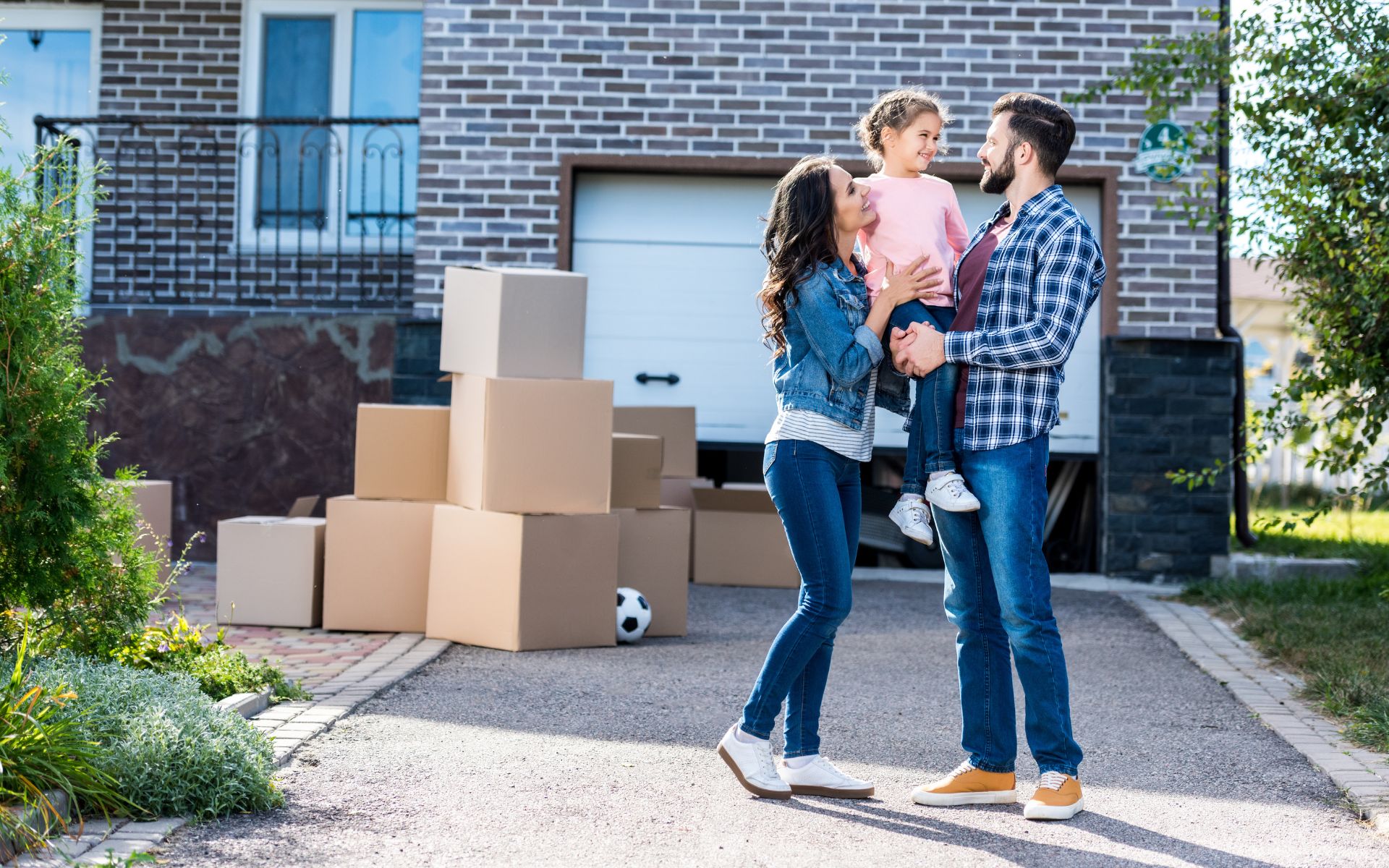 Family outside standing in a driveway with moving boxes